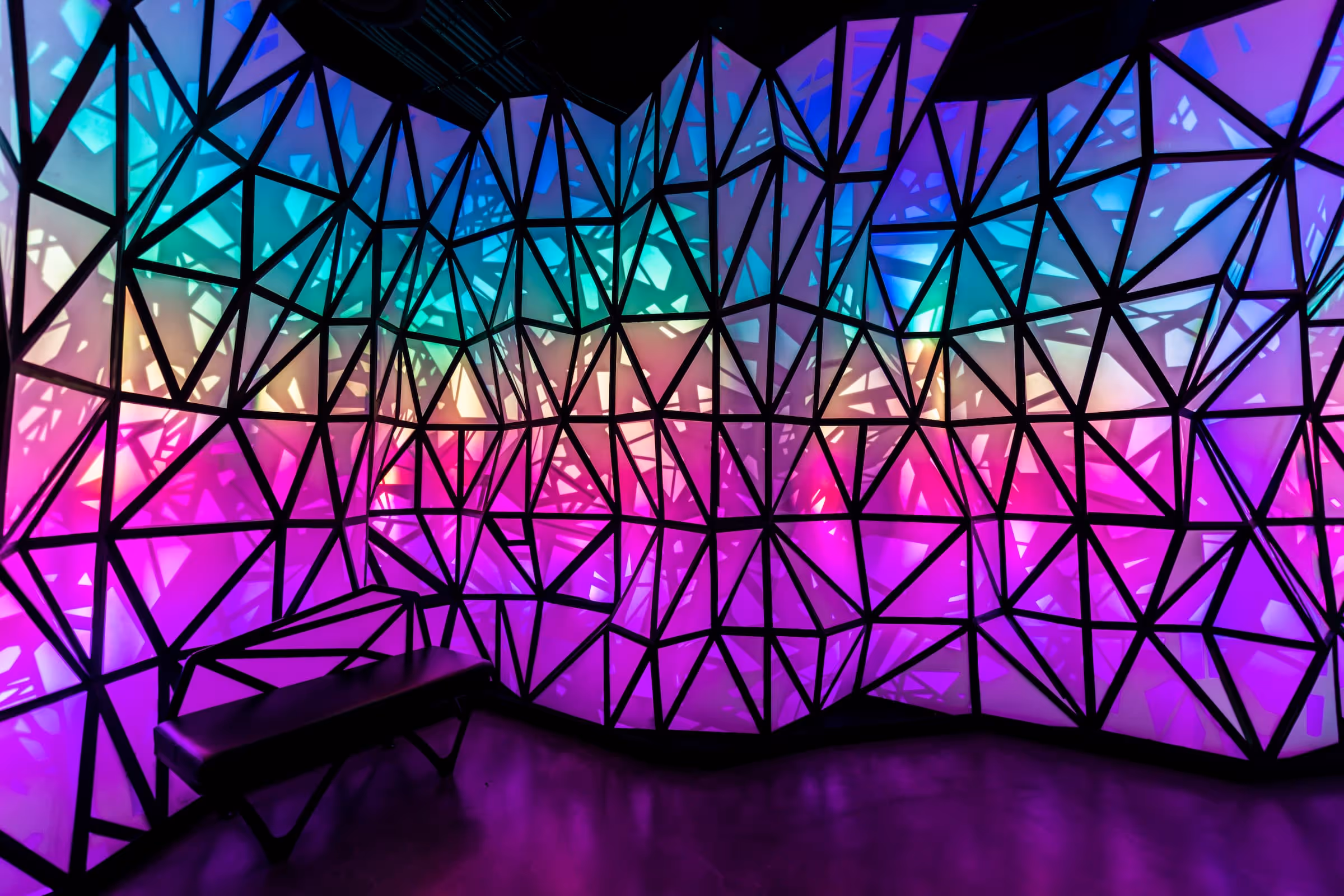 rainbow colors on a wall of triangles at differing angles inside Omega Mart