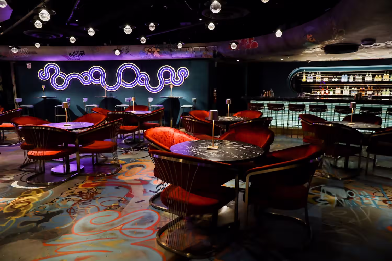 red chairs around round tables inside Sips with a Z at Meow Wolf Denver